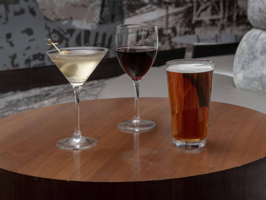 Three glasses of beverages on a round wooden table.