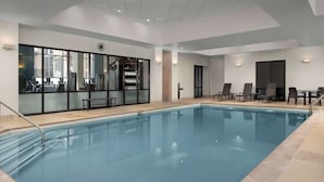 An indoor swimming pool with clear water, surrounded by lounge chairs and a seating area.