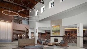 A spacious lobby with a central seating area, a fireplace, and a large abstract painting on the wall.