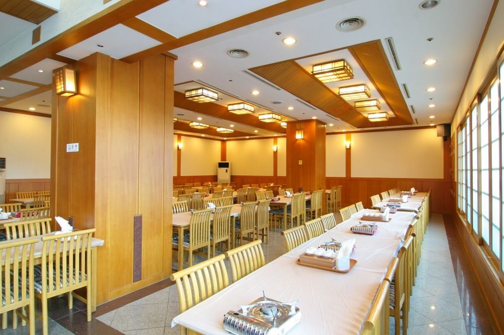 A conference room with long tables, chairs, and a large screen.