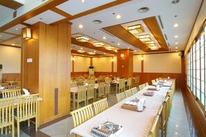Un salón de conferencias con largas mesas, sillas y una pantalla grande.