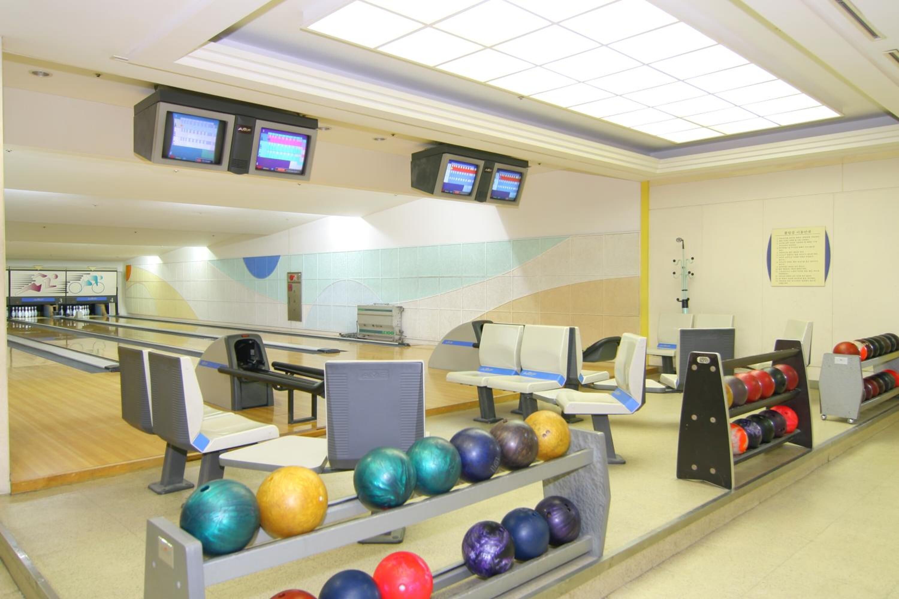 A bowling alley with multiple lanes, seating areas, and a bowling ball rack.