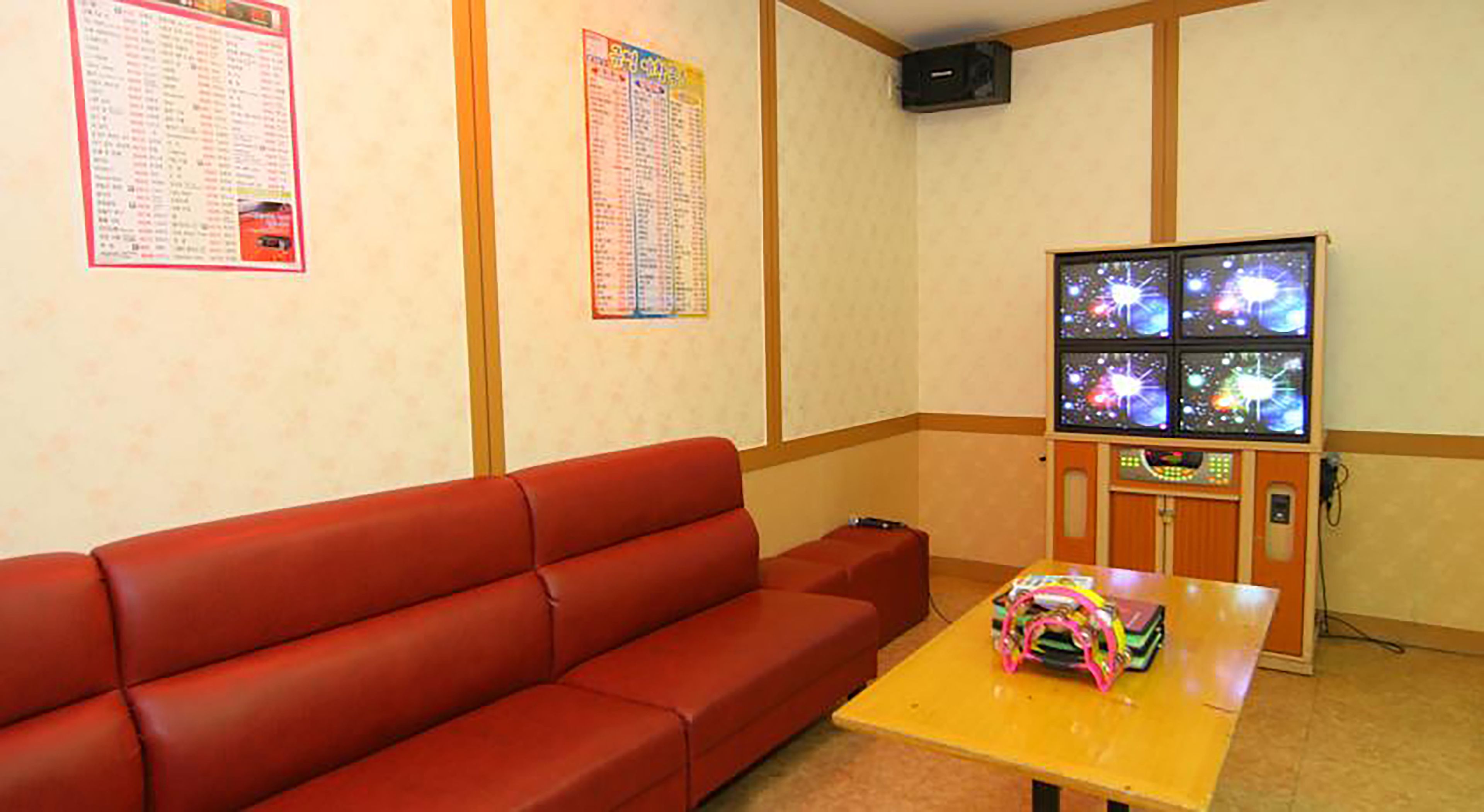 A room with a red sofa, a small table with a colorful object, and a wall-mounted screen displaying a space-themed image.