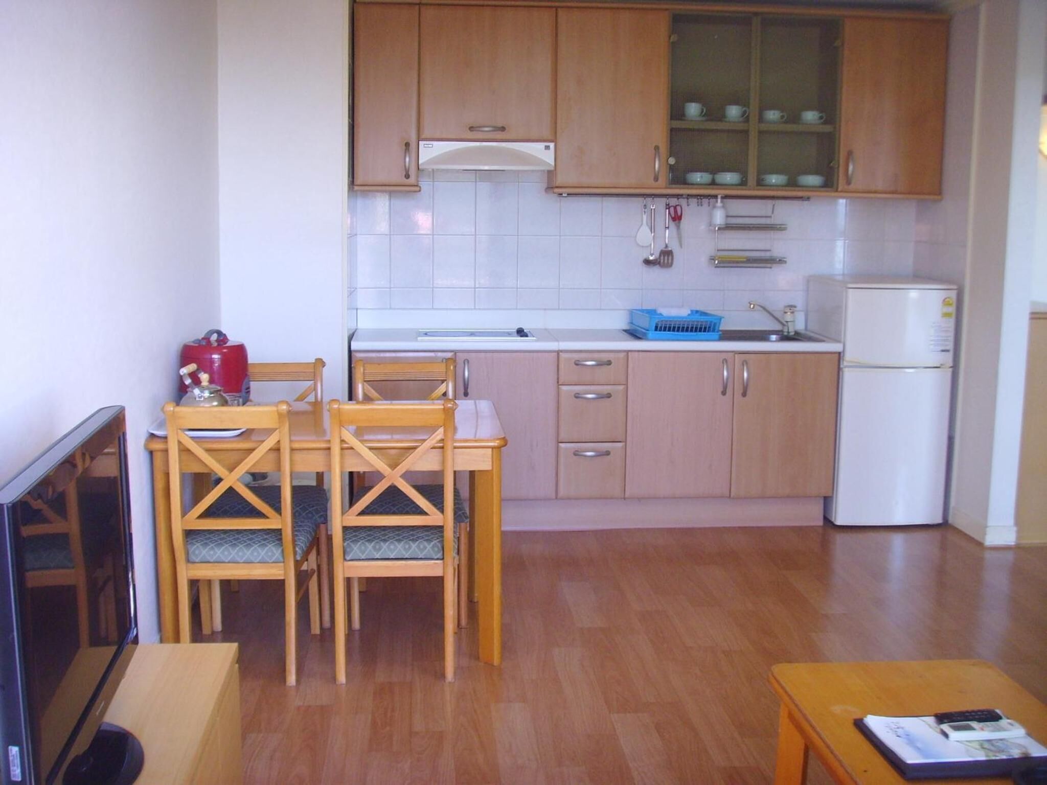 A compact kitchen with wooden cabinets, a built-in stove, a sink, and a refrigerator.