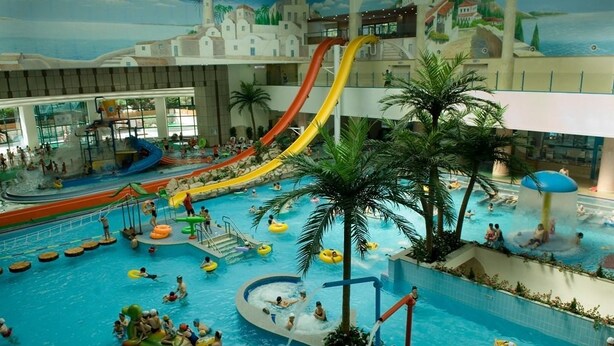 Een overdekt waterpark met meerdere glijbanen, zwembaden en waterattracties.