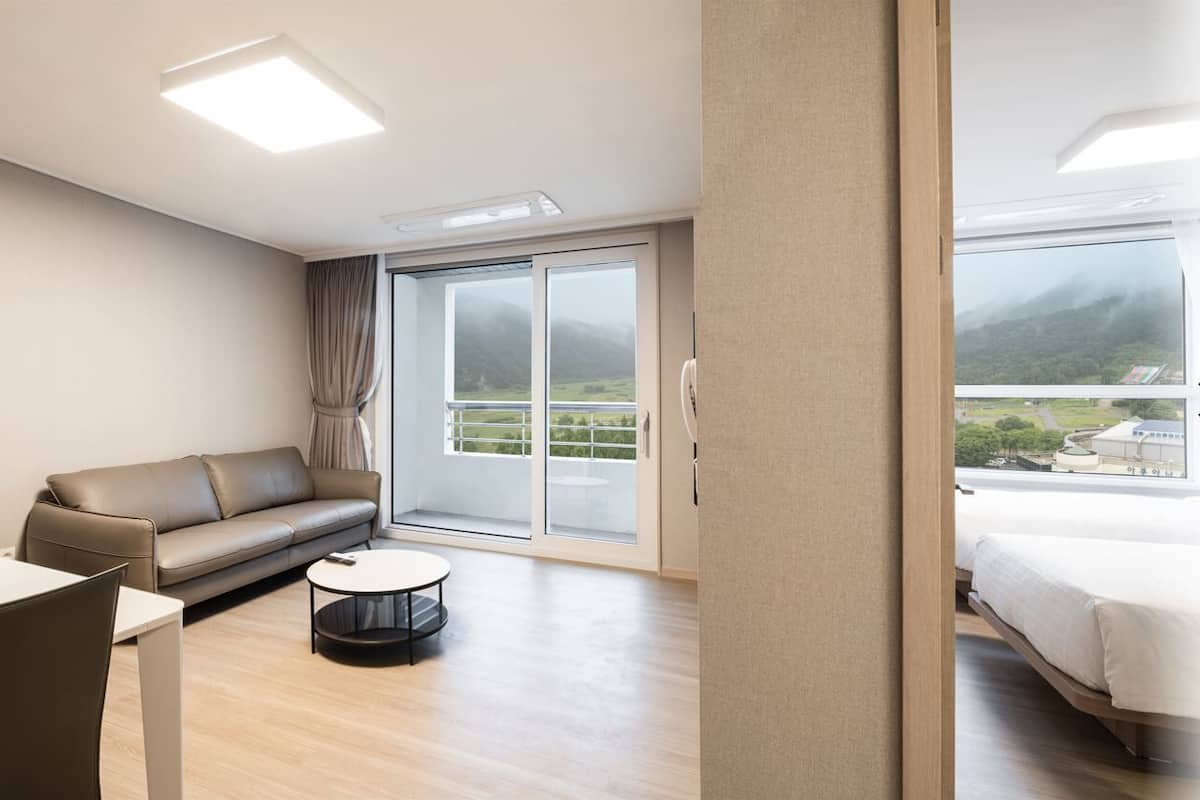 Una habitación de hotel moderna con sofá, una mesa de comedor, una mesita redonda y una cama.