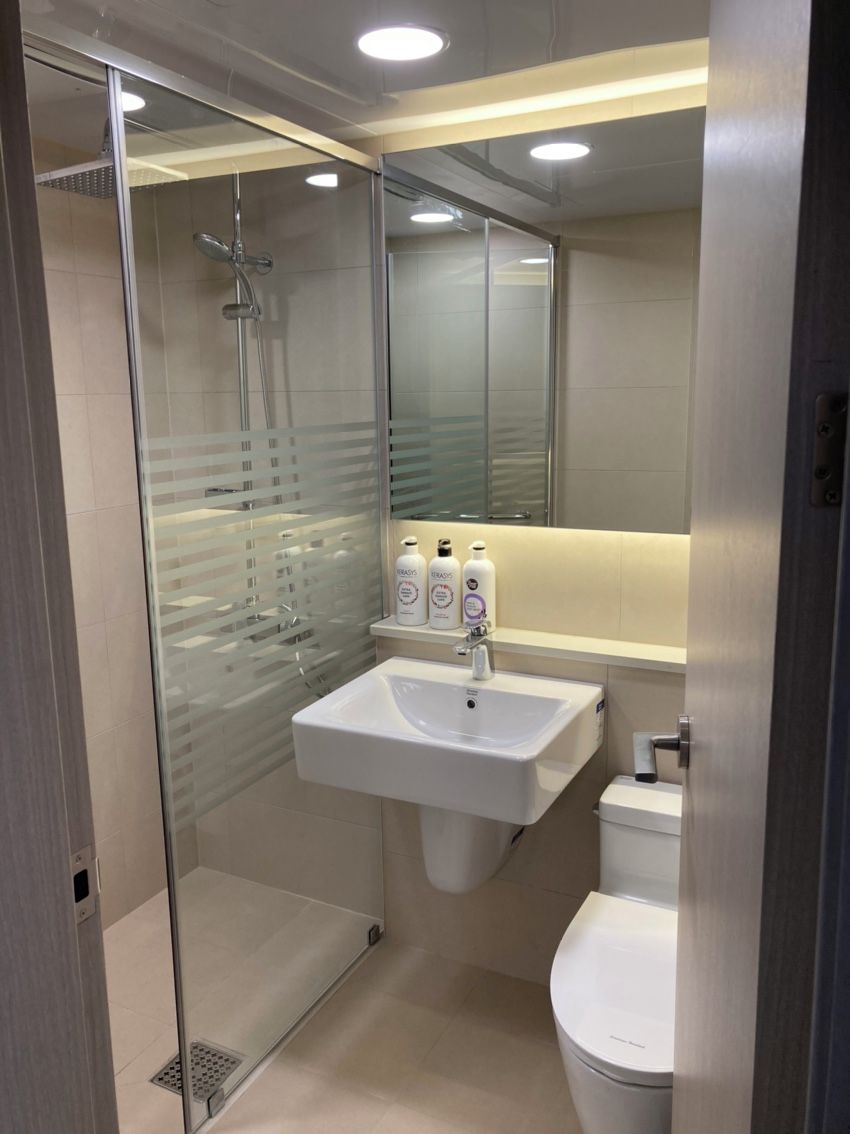 A modern bathroom with a glass-enclosed shower, a white sink, and a toilet.