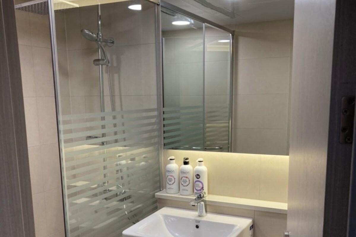 A modern bathroom with a glass-enclosed shower, a white sink, and a toilet.