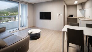 Een moderne hotelkamer met balkon, flatscreen-televisie, eethoek en kitchenette.