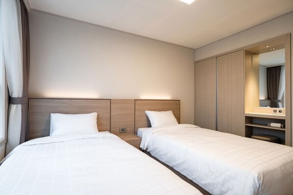 Una habitación de hotel con dos camas, un cabecero de madera, un espejo grande y un armario.