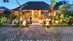 A traditional house with a tiled entrance, surrounded by lush greenery and two umbrellas. - New Pondok Sara Villas (Seminyak)