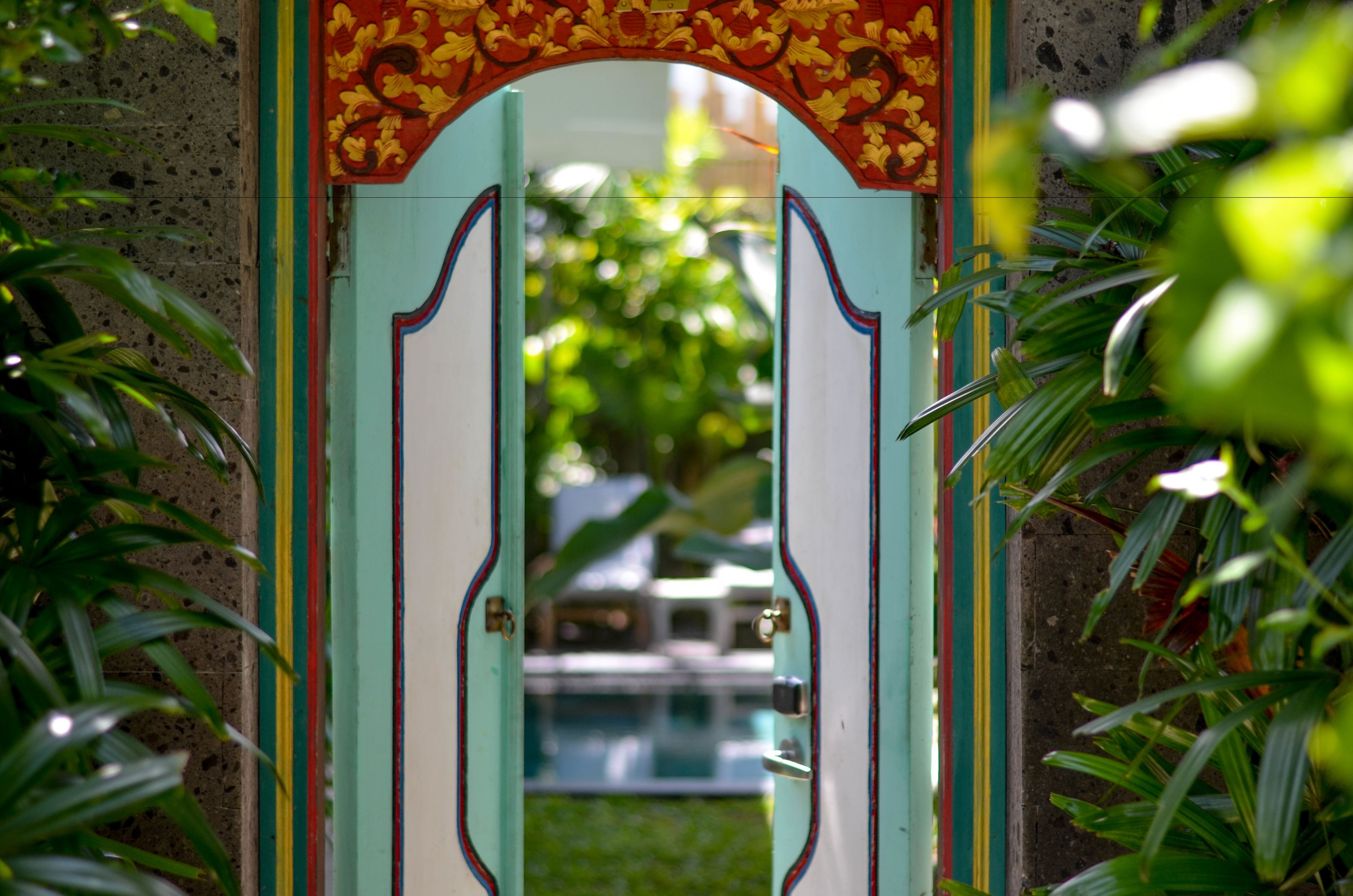 A doorway with a decorative arch and a view of a swimming pool in the background.