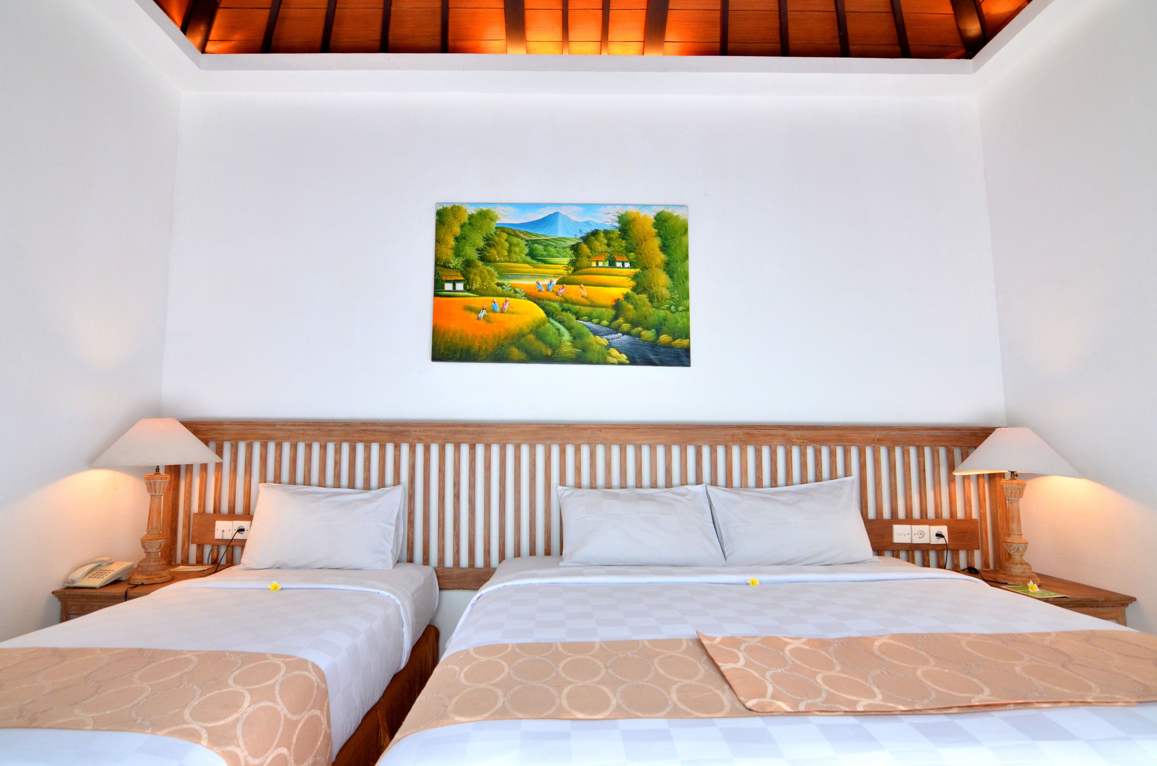 A hotel room with two beds, a wooden headboard, bedside lamps, and a painting of a landscape on the wall.