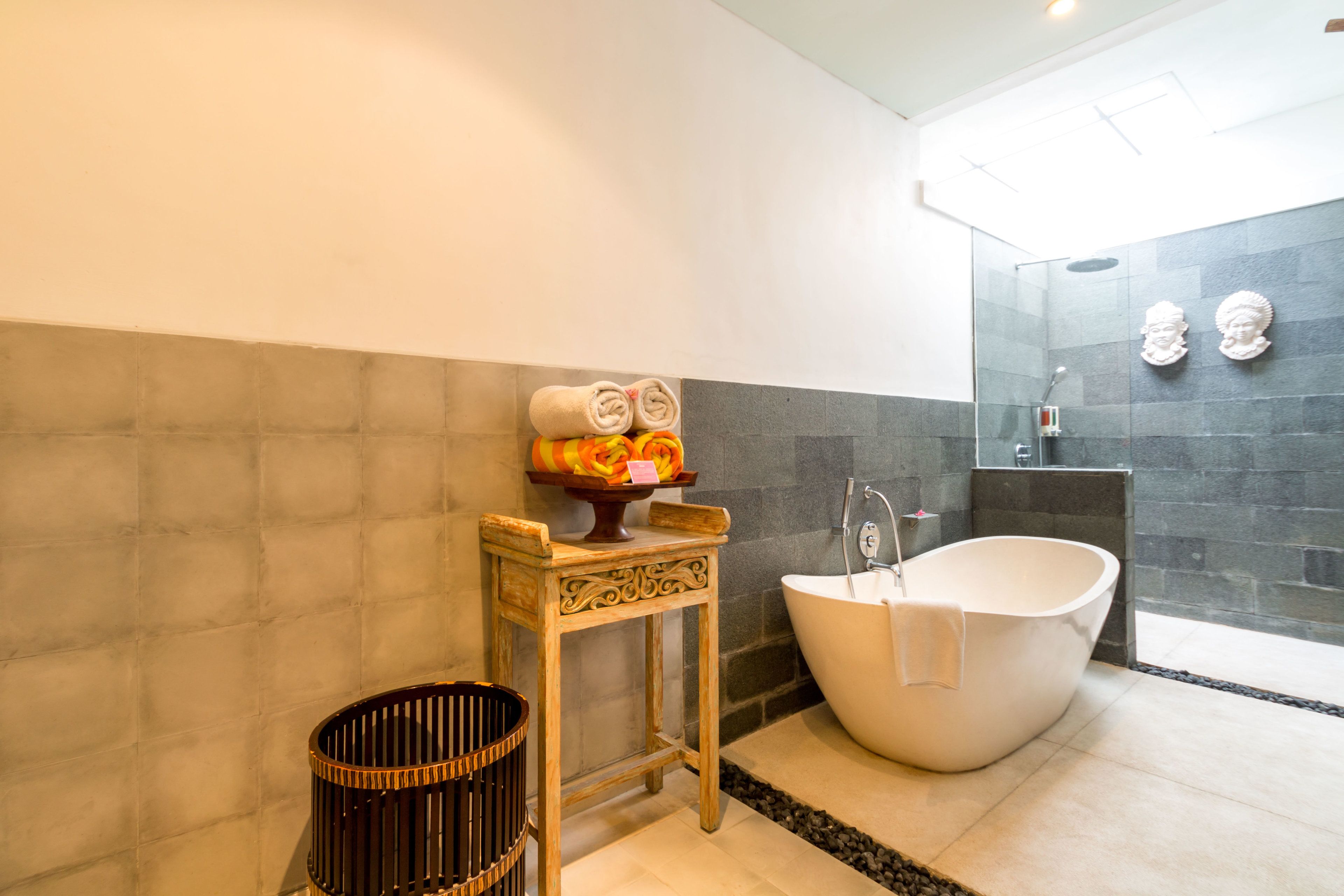 A modern bathroom with a freestanding bathtub, a small wooden vanity, and a glass shower enclosure.