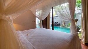A bedroom with a large bed, sheer curtains, and a view of a swimming pool. - New Pondok Sara Villas (Seminyak)