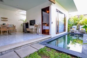 A modern home with a swimming pool, a dining area, and a living room with a TV. - New Pondok Sara Villas (Seminyak)