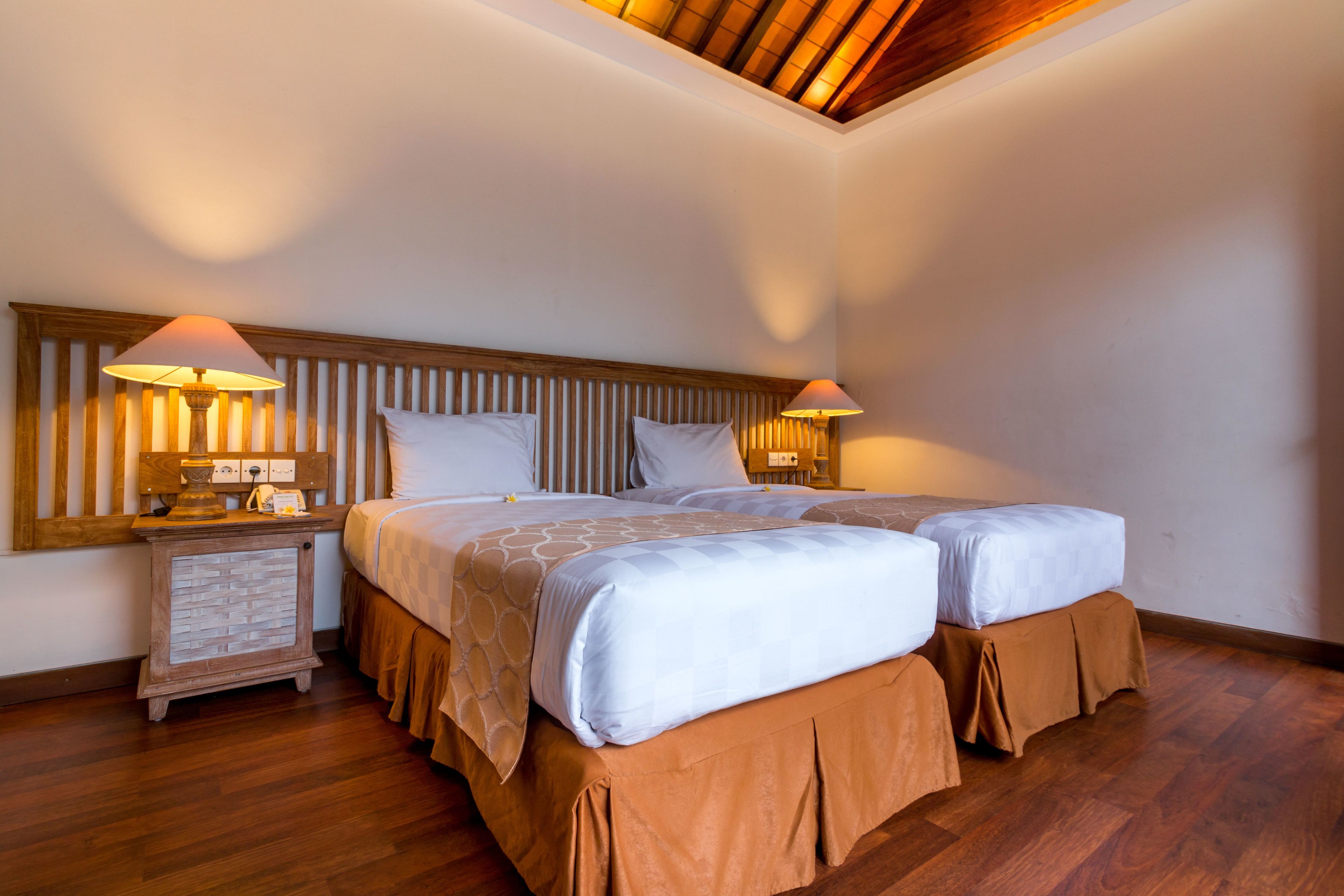 Une chambre d’hôtel avec deux lits, une tête de lit en bois, des lampes de chevet et une table de chevet.