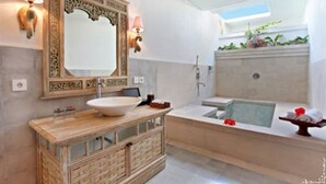 A modern bathroom with a large mirror, a wooden vanity, a bathtub, and a shower area. - New Pondok Sara Villas (Seminyak)