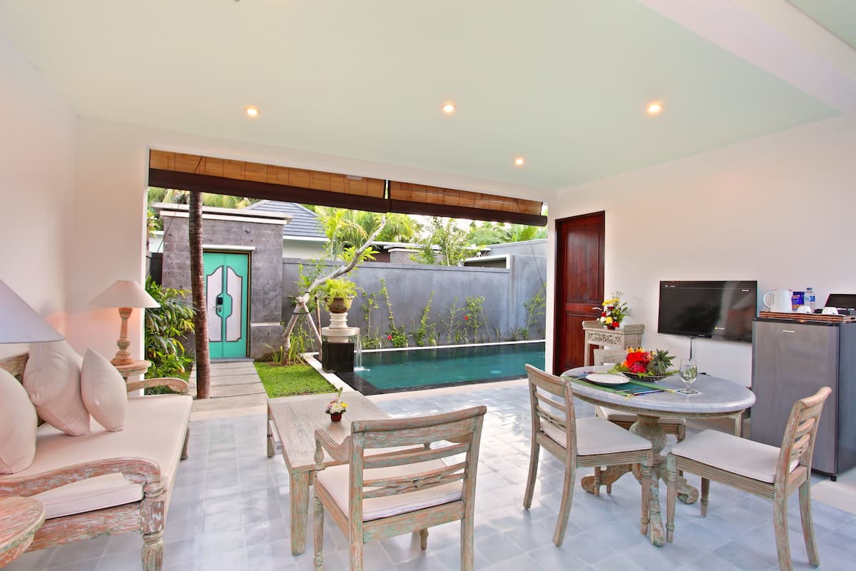 A modern kitchen with a TV, refrigerator, and dining area with a table and chairs.