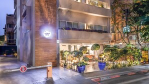 A modern hotel with a flat facade, multiple balconies, and outdoor seating areas. - Jacob Shenkin Hotel (Tel Aviv)