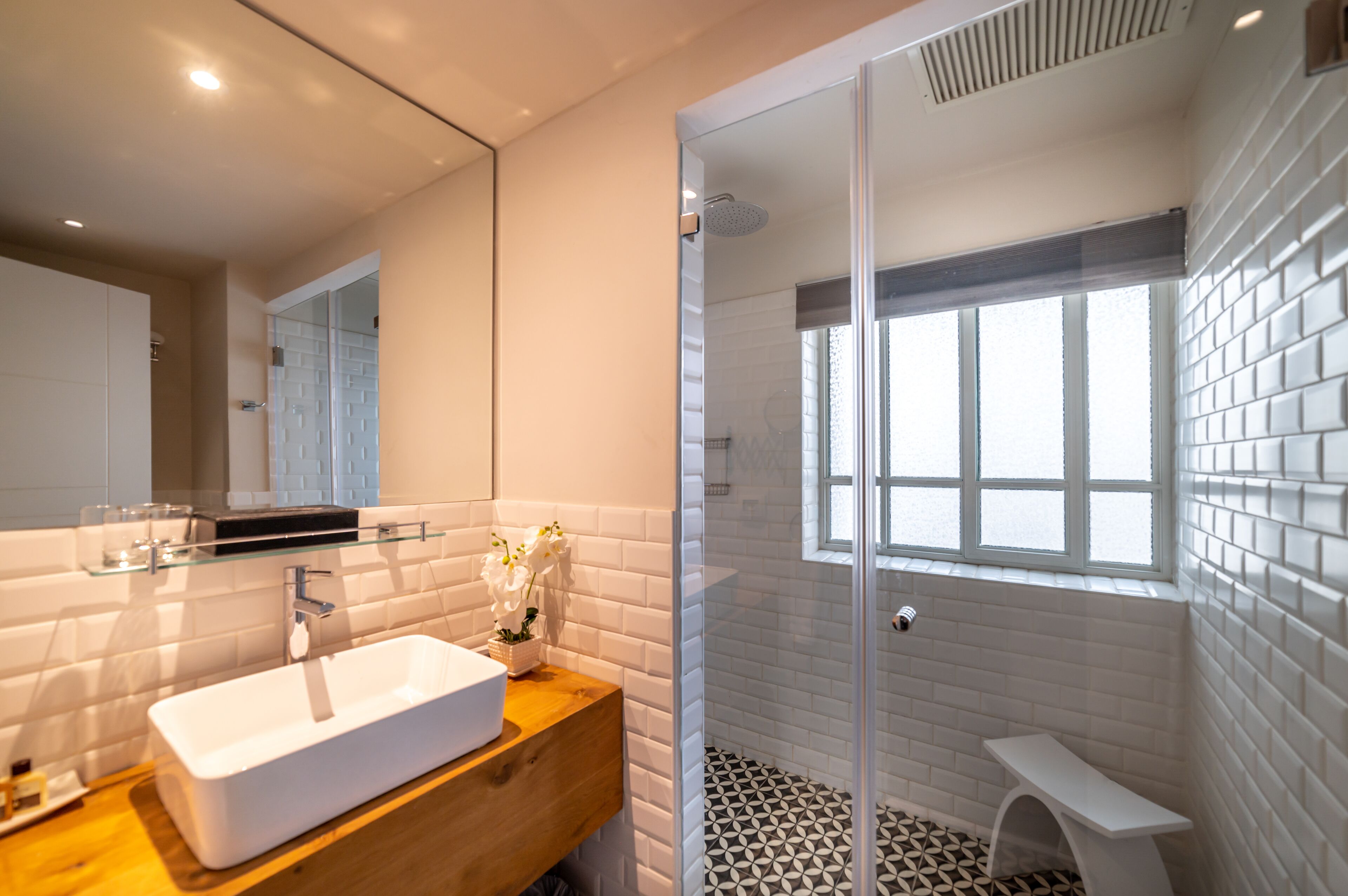 A modern bathroom with a glass-enclosed shower, a white sink, and a wooden vanity.