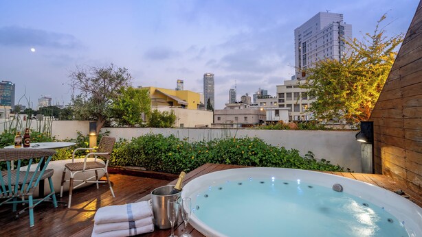 A rooftop terrace with a hot tub, seating area, and a view of the city skyline. - Jacob Shenkin Hotel (Tel Aviv)
