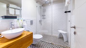 Un bagno moderno con cabina doccia in vetro, lavabo bianco e pavimento decorato.
