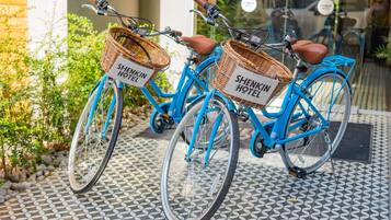 Two bicycles with baskets labeled "Shenkin Hotel" parked on a patterned tile floor.