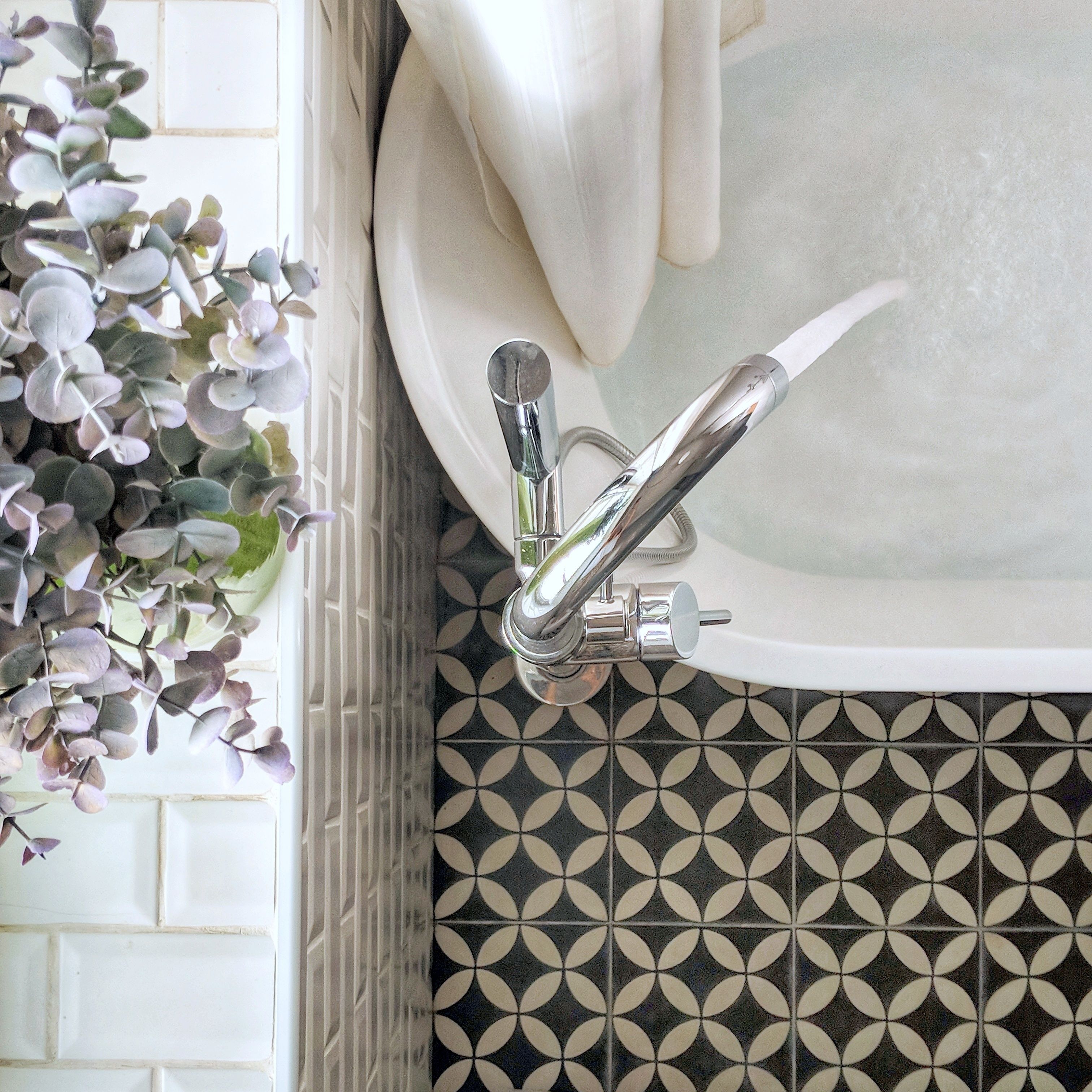 Un bagno con un moderno lavandino, un rubinetto cromato e piastrelle decorate.