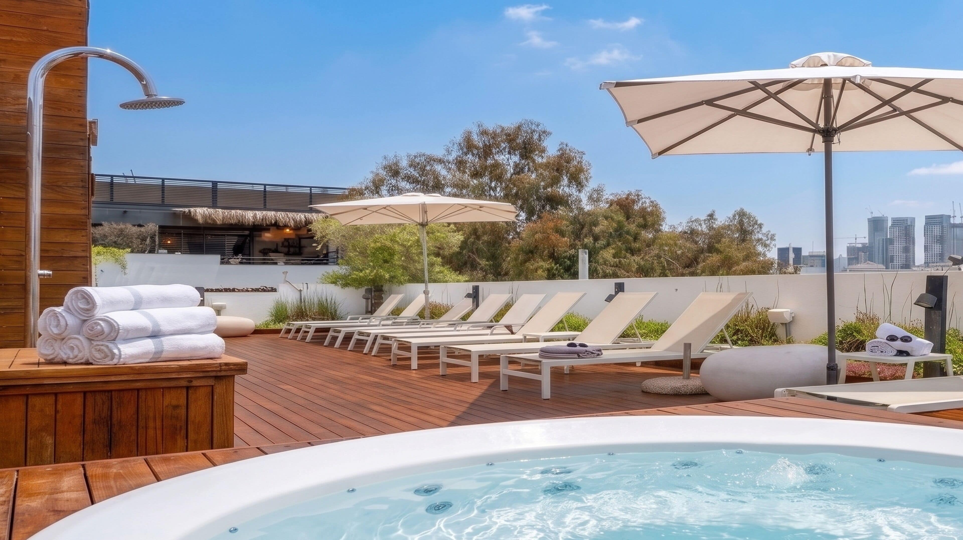 Une terrasse sur le toit équipée d’un jacuzzi, de chaises longues et de parasols.