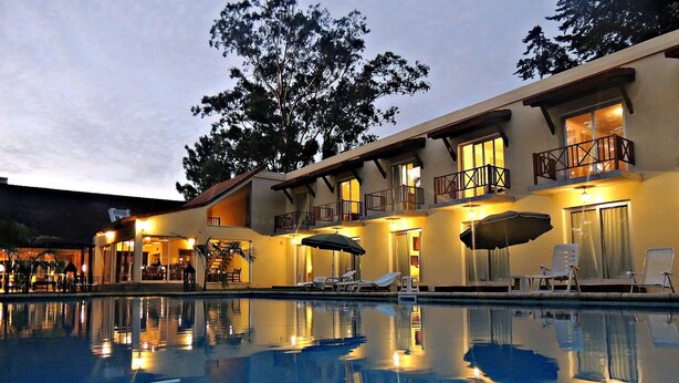 Um hotel com piscina, área de estar externa e varanda com guarda-corpo.