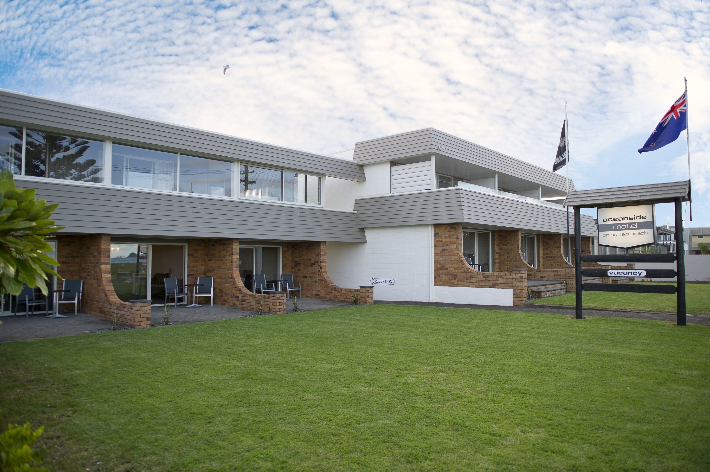 A modern motel with a reception area, outdoor seating, and a flag.