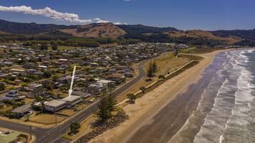 A coastal town with a beach, houses, and a road leading to the shore.