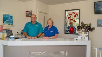 A reception desk with a sign for a Cathedral Cove Tour priced at $90.
