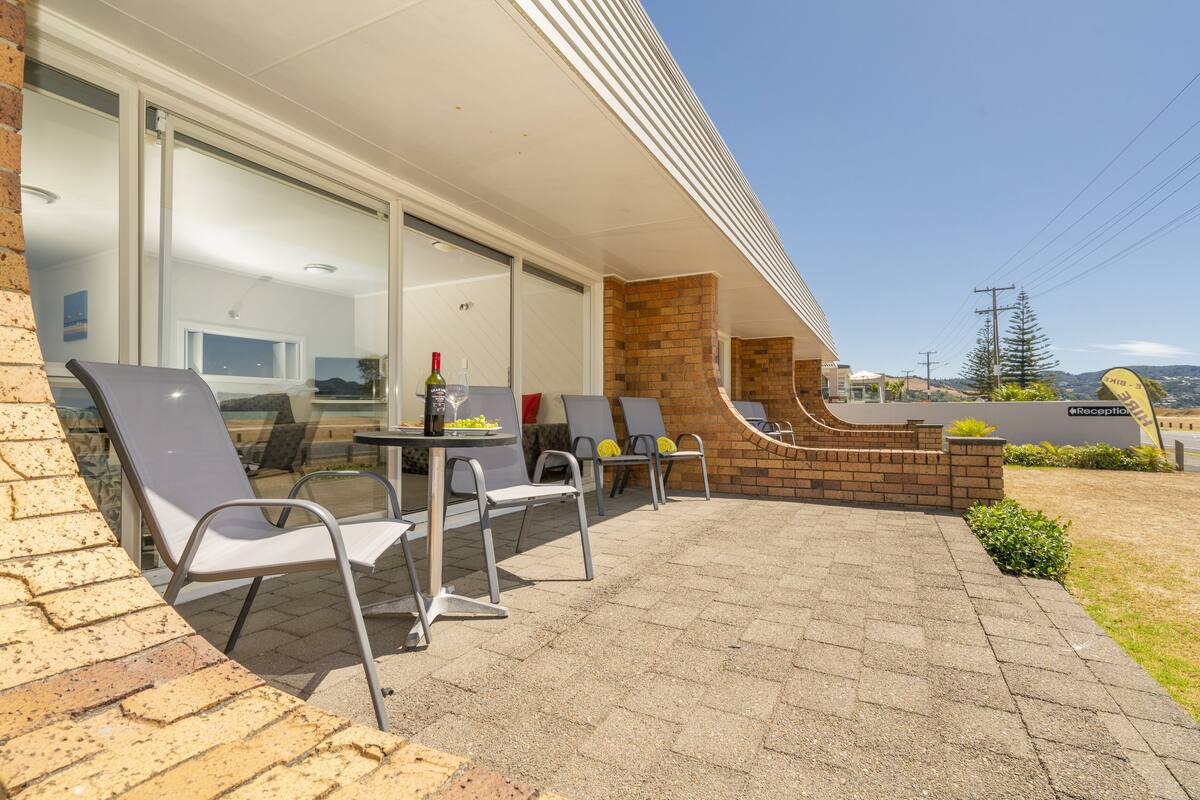 An outdoor patio with seating and a table, a brick wall, and a clear view of the surrounding area.