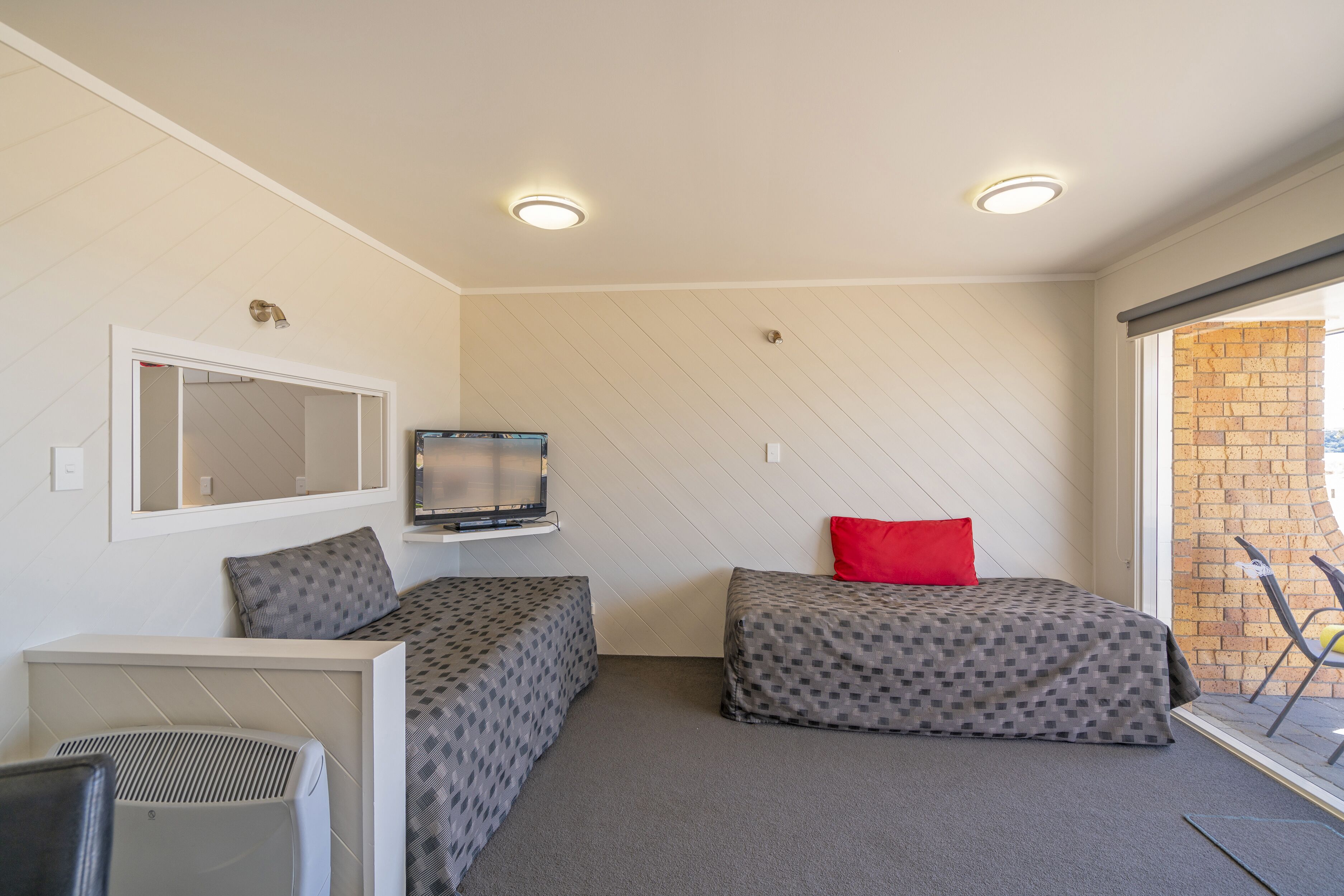 Una habitación compacta con dos camas, televisión y una pequeña zona de estar.