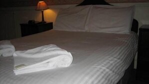 Un lit bien fait, avec du linge de lit blanc et une serviette pliée posée sur le côté.