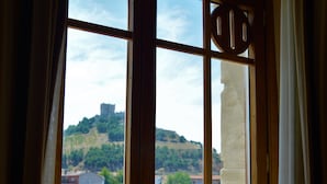 A window with a view of a town, including buildings and a hill with a castle-like structure. - AM Ribera del Duero (Penafiel)
