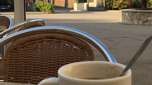 A table with a Candelas branded mug, wicker chairs, and a view of a castle on a hill. - AM Ribera del Duero (Penafiel)