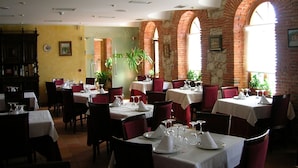 A restaurant with brick arches, white tablecloths, and red chairs. - AM Ribera del Duero (Penafiel)