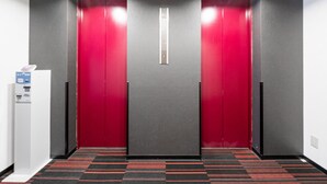 A hallway with red doors, a white machine, and a patterned carpet. - Tabist Annex Hotel Tetora Hakodate Goryokaku (Hakodate)