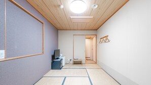 A room with tatami mats, a desk with a computer, a TV, and a small table with a cup. - Tabist Annex Hotel Tetora Hakodate Goryokaku (Hakodate)
