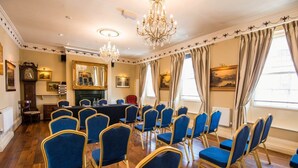Un salón de conferencias con sillas azules, una chimenea y candelabros.