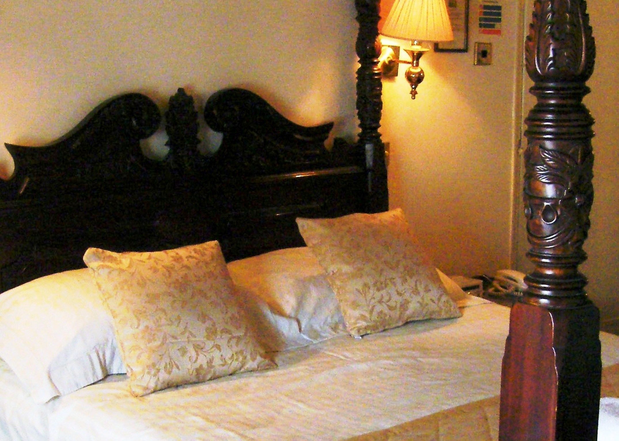 A four-poster bed with a dark wooden headboard and two decorative pillows.