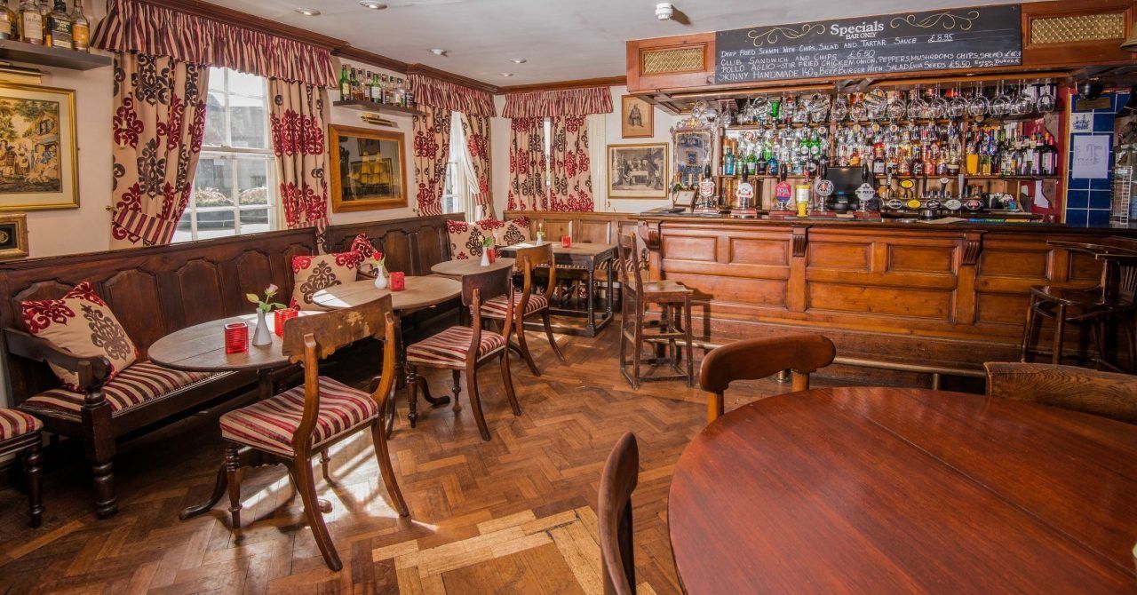 A cozy bar area with wooden furniture, a bar counter, and a menu board.