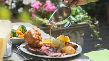 A plate of food with roast beef, Yorkshire pudding, mashed potatoes, and vegetables.