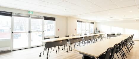Una sala de conferencias con una larga mesa, sillas y ventanas amplias.