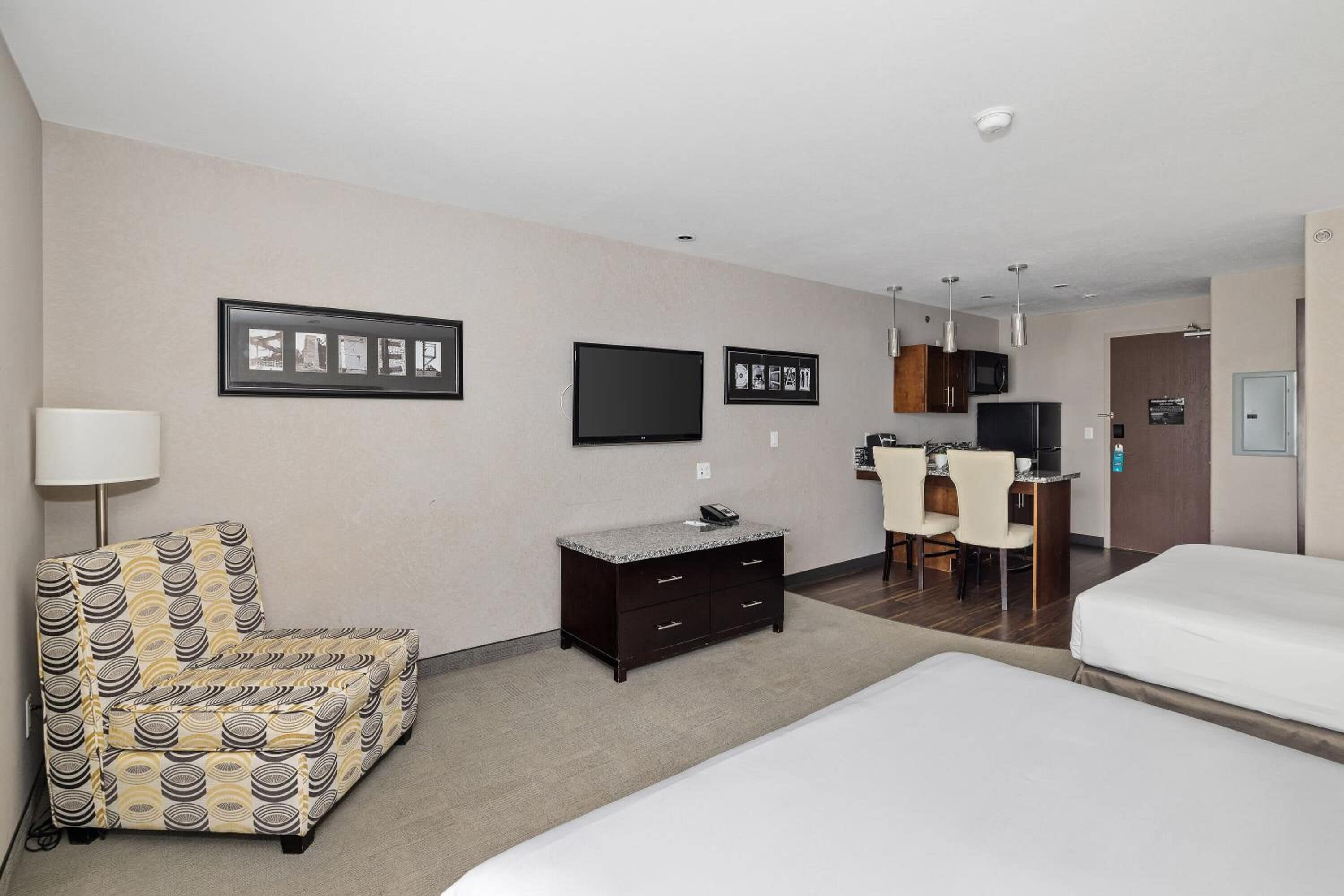 A hotel room with a bed, a desk, a chair, a TV, and a small cabinet.