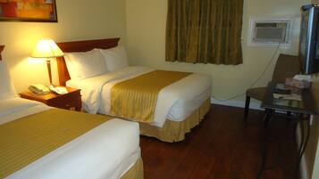 A hotel room with two beds, a desk, a chair, a lamp, a telephone, and a painting on the wall.