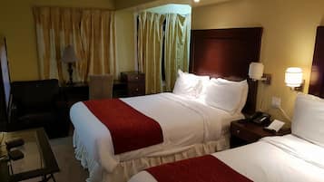 Quarto de hotel com duas camas, uma escrivaninha, uma cadeira, um abajur e uma mesa de cabeceira com telefone.